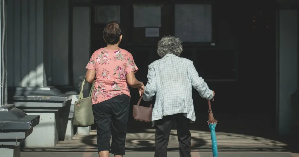 Duas senhoras caminham juntas em direção à porta de um prédio