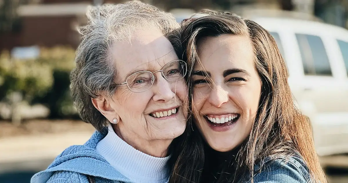 Filha abraça a mãe idosa, as duas sorrindo