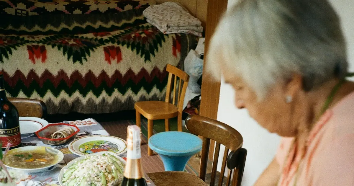 Senhora idosa sentada à mesa diante de um prato de comida