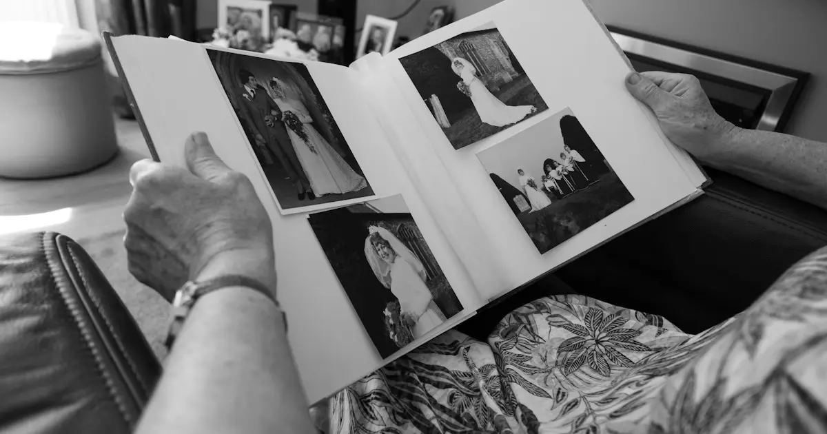 Mãos de uma pessoa idosa folheando um álbum de fotos de casamento em preto e branco